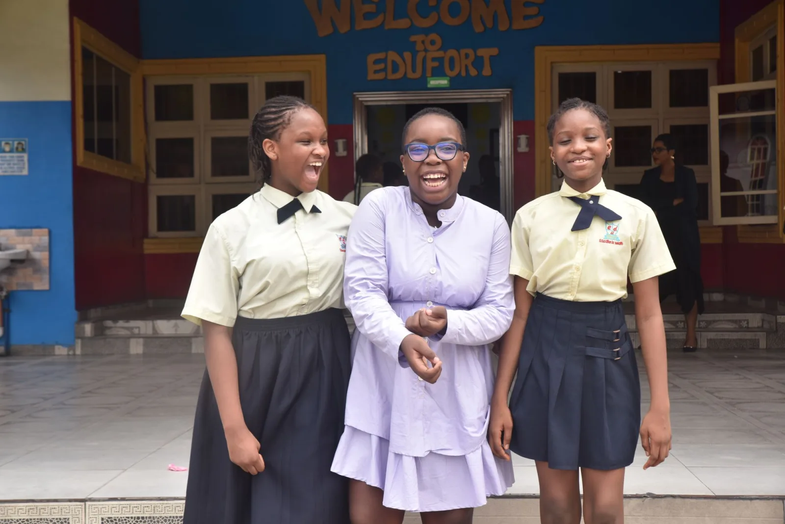 Three secondary school girls in uniform laughing together outside their school. Photo by Amarachi Dimkpa on Pexels.