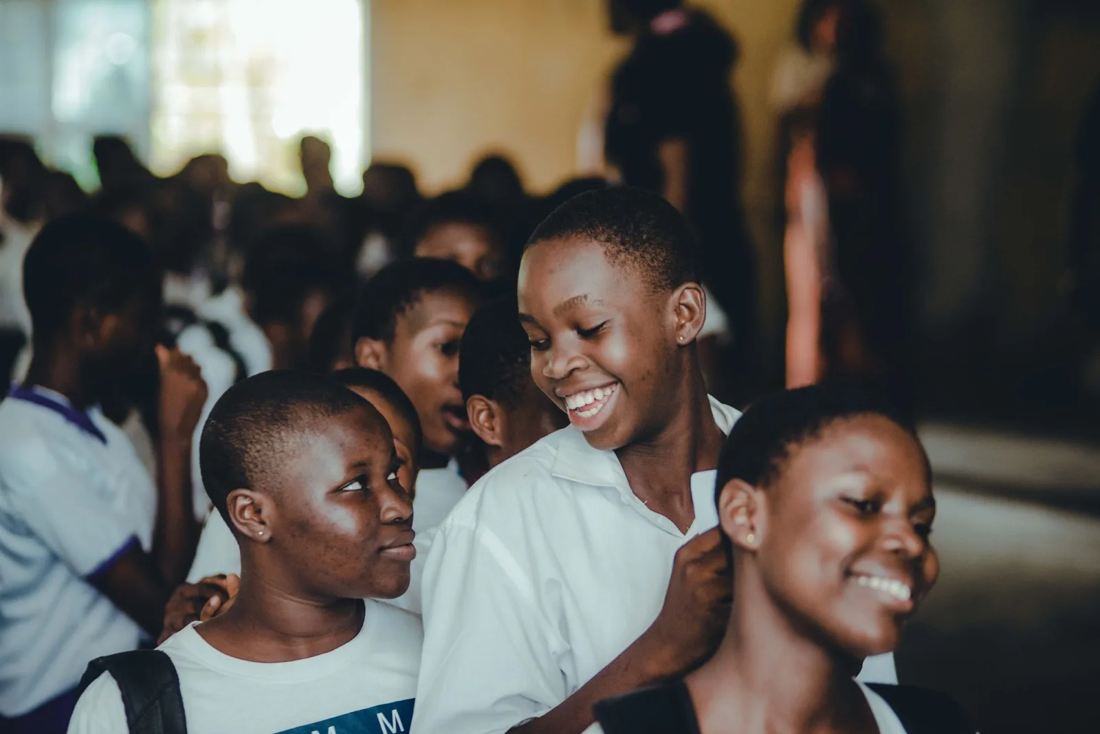 A group of secondary school girls laughing together in their school hall. Photo by Tosin Olowoleni on Pexels.